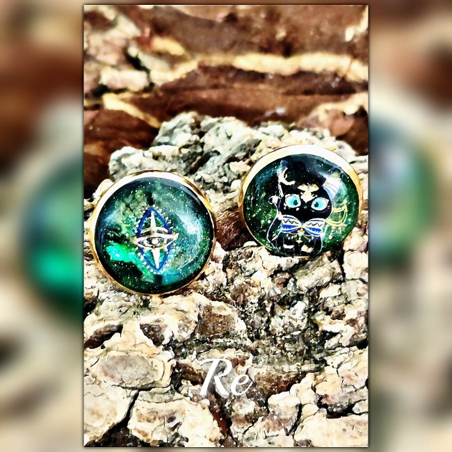 Gros plan boucles d’oreilles Ré – Bijou solaire égyptien artisanal | Les Fantaisies d'A Gros plan sur les clous d’oreilles Ré artisanaux en camaïeu de vert et doré avec œil solaire et éclipse indigo