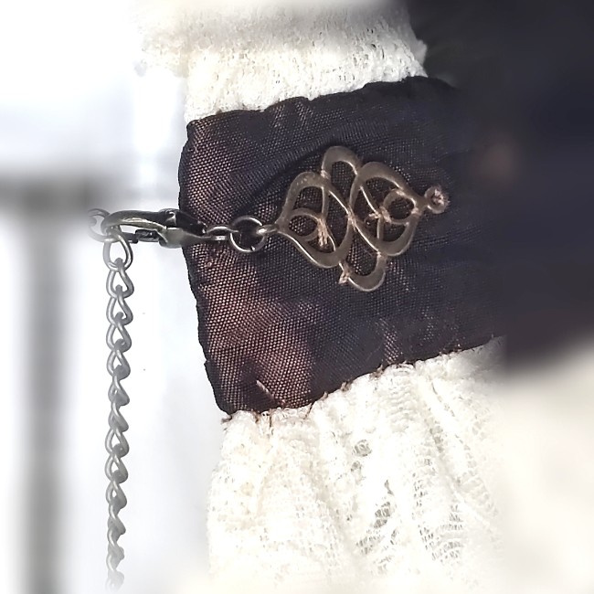 Zoom sur l’arrière du collier Cassandre, fermeture mousqueton en laiton et application en laiton brodée sur le bandeau