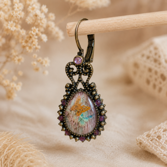 Zoom sur la première boucle d'oreille Le Premier Envol mettant en valeur les détails du cabochon et de la monture bronze vieilli.