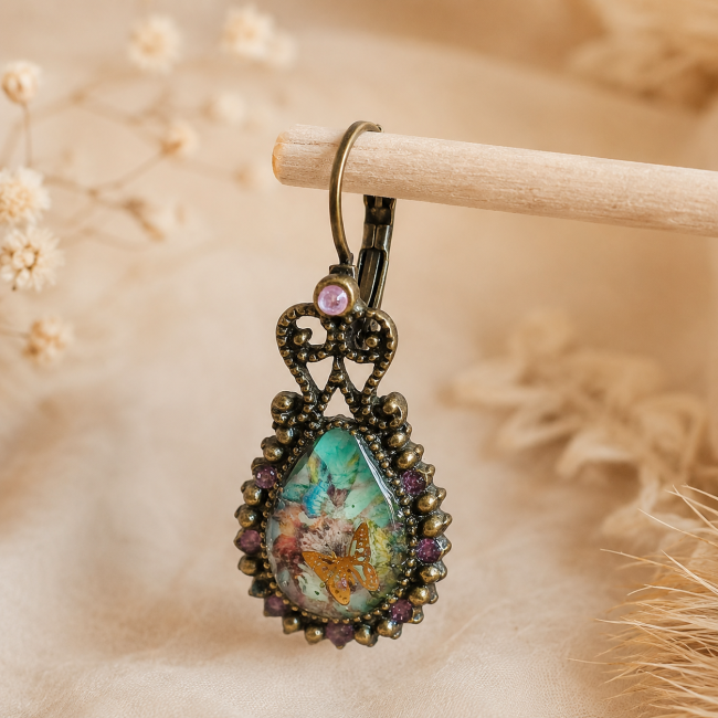 Zoom sur la deuxième boucle d'oreille Le Premier Envol mettant en valeur les détails du cabochon et de la monture bronze vieilli.