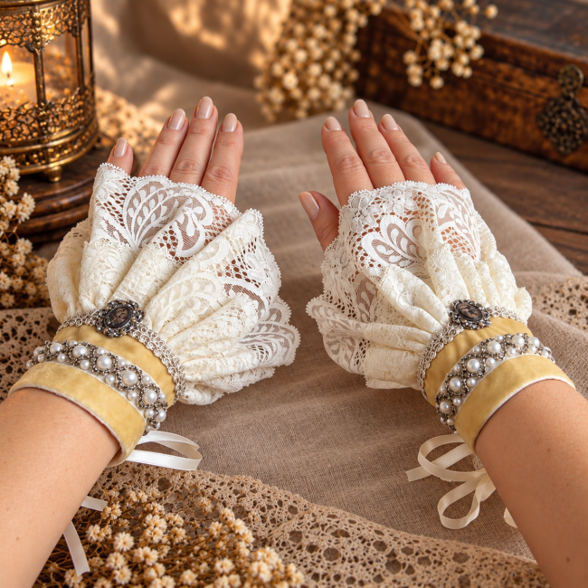Paire de manchettes Le Dernier Regard d’Eurydice portée aux deux poignets, en dentelle ivoire, velours bistre, perles nacrées et détails argentés, collection Les Élégies de l’Antiquité.