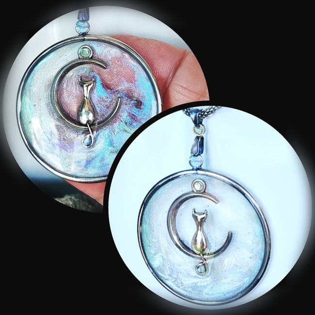  Phosphoros, un bijou entre rêve et lumière. Chaque collier met en valeur un pendentif circulaire en acier inoxydable, minutieusement émaillé à la main dans un subtil jeu de transparence bleu pâle et nacrée. Au cœur de ce pendentif, un chat délicatement p