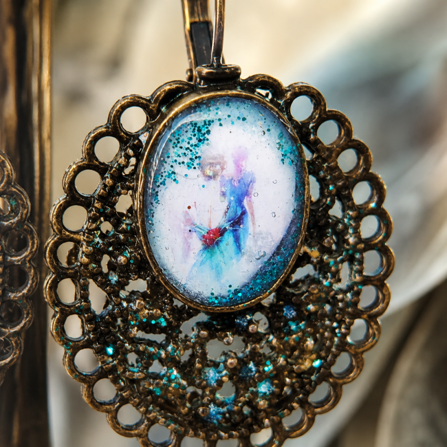 Détail du cabochon – Le Passage des Pétales Gros plan sur le cabochon illustré aux teintes pastel et scintillances bleu turquoise des boucles d'oreilles Le Passage des Pétales.