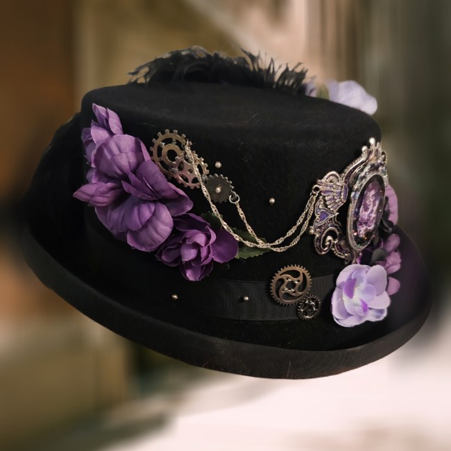 Détails steampunk du chapeau Mina – Engrenages et broderies artisanales Chapeau steampunk Mina côté droit avec chaînettes argentées, engrenages métalliques et fleurs violettes brodées à la main