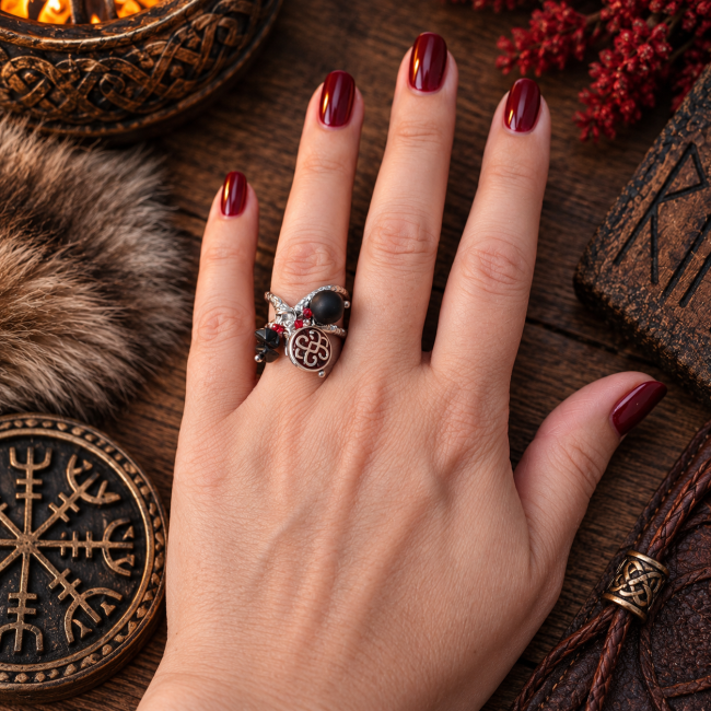 Bague viking L’Œil d’Odin en onyx portée L’Œil d’Odin porté au doigt, une bague artisanale d’inspiration viking associant onyx noir, métal argenté et touches rouges dans un univers nordique.