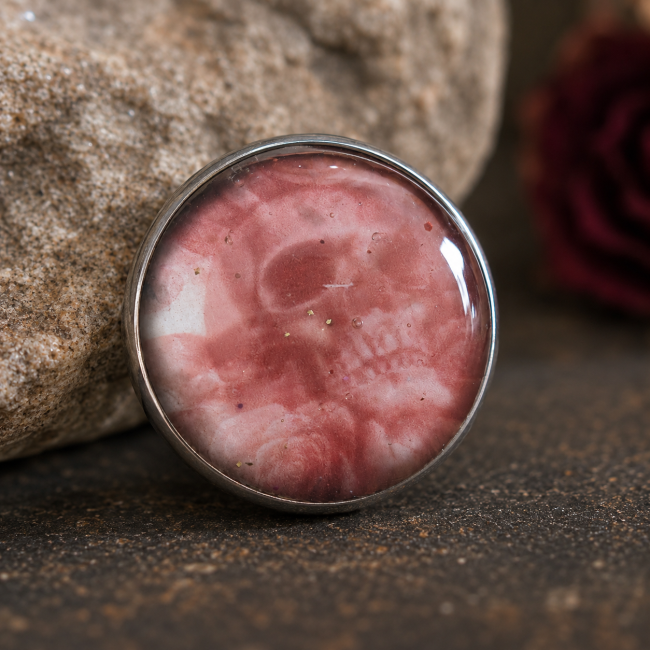 Cabochon crâne gothique La Dame aux Roses de Cendre Cabochon illustré représentant un crâne dans des nuances de rose cendré sur fond de dentelle noire.