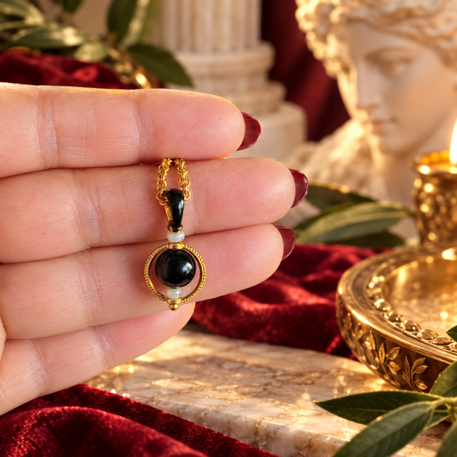 Collier Chandra – Pendentif noir et perles d'obsidienne Détail du pendentif secondaire noir brillant entouré de métal doré sur le collier double Chandra, accompagné de perles en obsidienne noire.