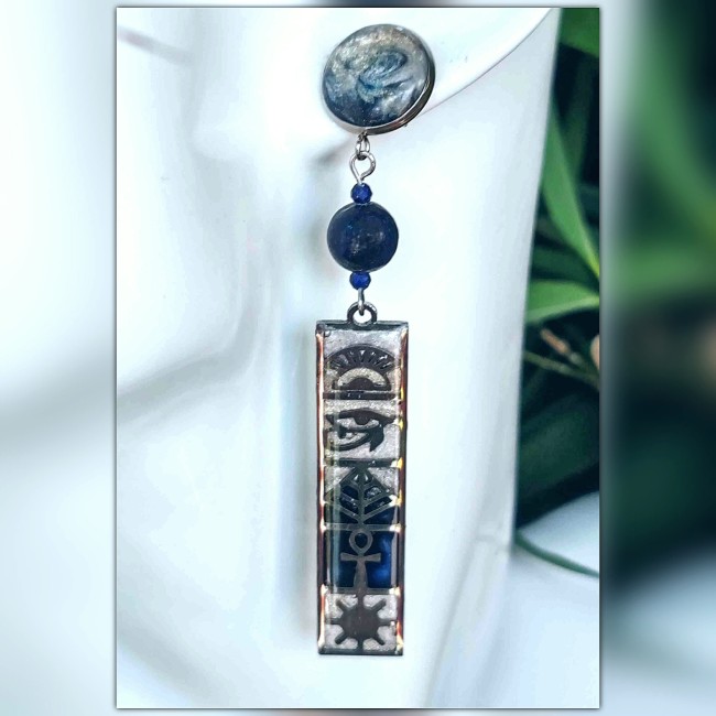 Présentation des boucles d'oreilles ésotériques égyptiennes collection « Horus» Lapis Lazuli' sur présentoir qui met en valeur l'émaillage du cabochon en spirale bleu sombre et ivoire nacrée, l'enfilage de perles en Lapi Lazuli et le pendant orné de hiéro