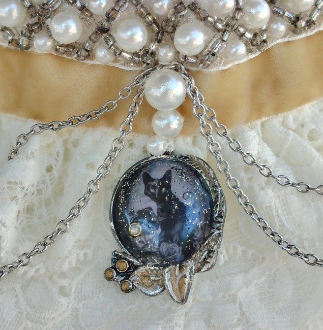 Zoom sur le pendentif circulaire de L’Étoile de Rhiannon orné d’un cabochon émaillé à la main représentant un chat noir