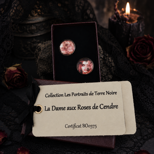Coffret cadeau La Dame aux Roses de Cendre – Les Portraits de Terre Noire Boucles d'oreilles La Dame aux Roses de Cendre présentées dans leur coffret avec certificat d'authenticité sur décor gothique.