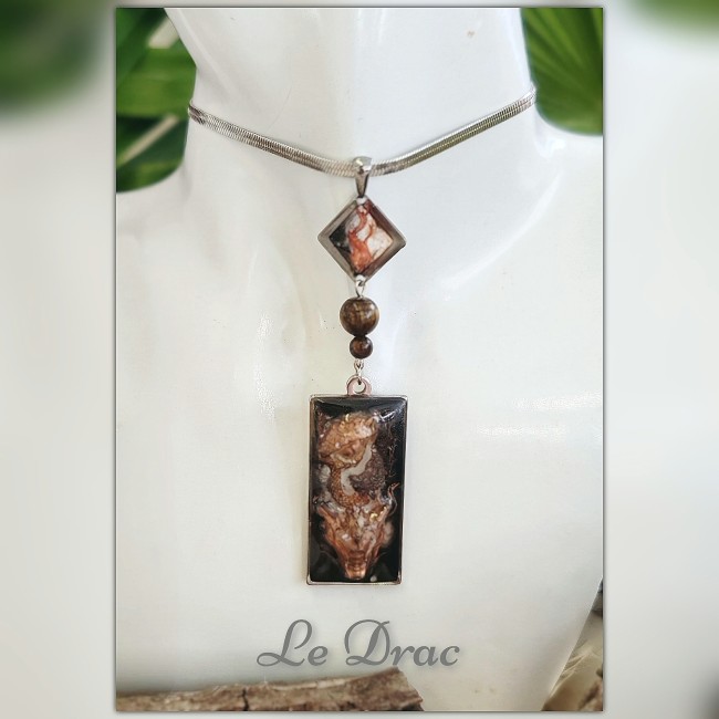 Collier Le Drac – Fantaisies d’A. Collier Le Drac, inspiré du dragon des abysses : pendentif sculpté en 3D, gemmes Œil de Tigre, émail transparent et acier inoxydable rhodié. Une création artisanale mythologique signée Fantaisies d’A.