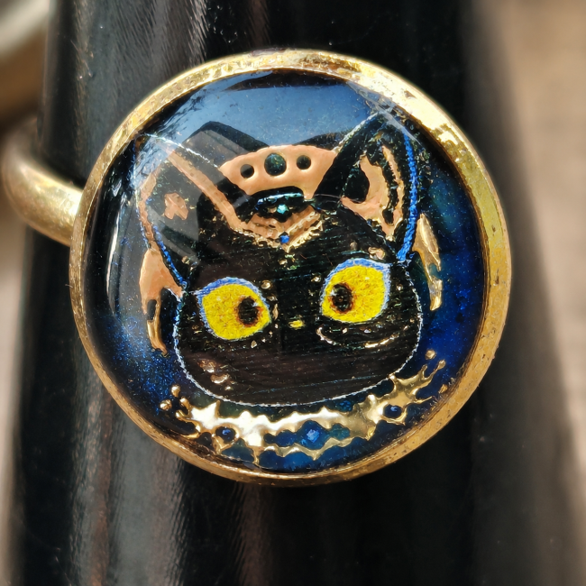 L’Ankh Éternel – Cabochon Bastet émaillé à la main Bague L’Ankh Éternel avec cabochon émaillé représentant la tête de Bastet sur fond bleu indigo