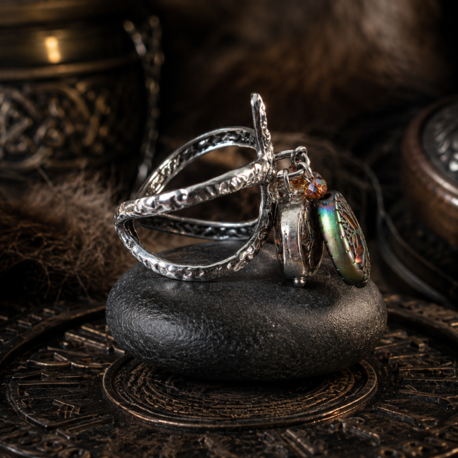 Vue de profil de la bague viking femme « Le Puits de Mimir », révélant sa structure réglable en acier inoxydable martelé et ses breloques dans un décor viking sombre et raffiné.