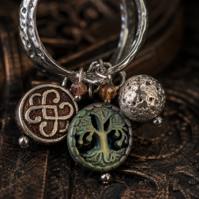 Gros plan sur les breloques de la bague viking « Le Puits de Mimir », avec motif de nœud celtique, Arbre de Vie, éléments émaillés, perles et hématite véritable.