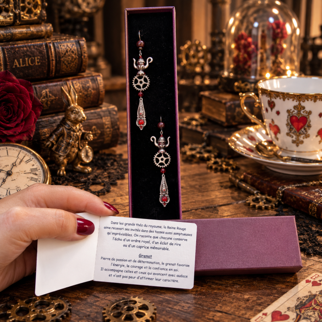 Boucles d’oreilles Les Tasses de la Reine Rouge dans leur écrin Les Tasses de la Reine Rouge, boucles d’oreilles de la collection Les Merveilles d’Alice, présentées dans leur écrin avec leur carte d’identification. Une présentation élégante aux accents steampunk, mettant en valeur les détails du bijou et son grenat.