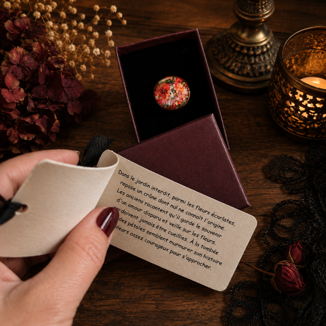 Le Crâne Écarlate – Bague artisanale présentée dans son écrin avec sa légende Bague Le Crâne Écarlate présentée dans son écrin avec carte de la légende