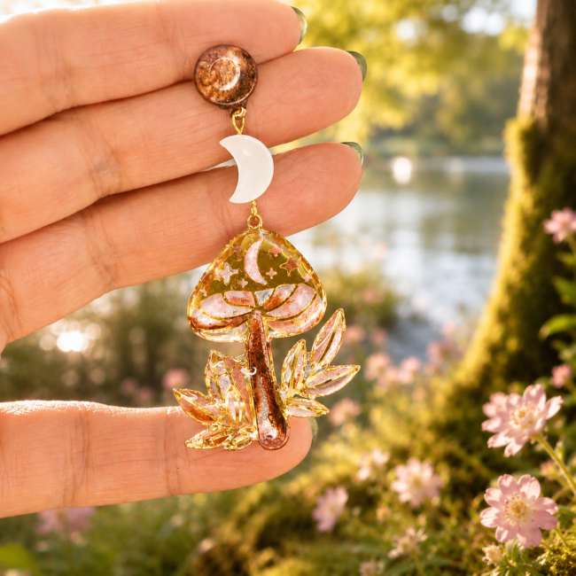 Détail de la boucle d’oreille L’Éclat des Fées avec croissant de lune en nacre et champignon émaillé à la main façon vitrail