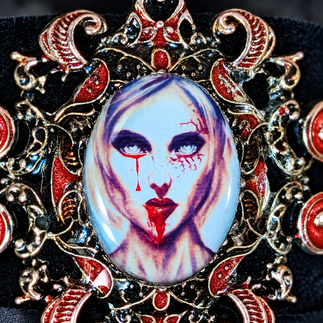 Gros plan sur le portrait ovale d’une vampire au teint pâle, aux yeux soulignés de noir, aux lèvres rouge sang et aux traces rouges, entouré de volutes métalliques et d’ornements rouges.