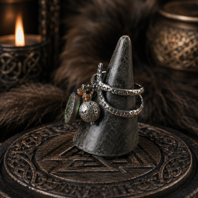 Bague viking femme « Le Puits de Mimir » présentée sur un support, avec son acier inoxydable martelé, ses breloques et ses éléments en hématite véritable, dans une ambiance nordique immersive.