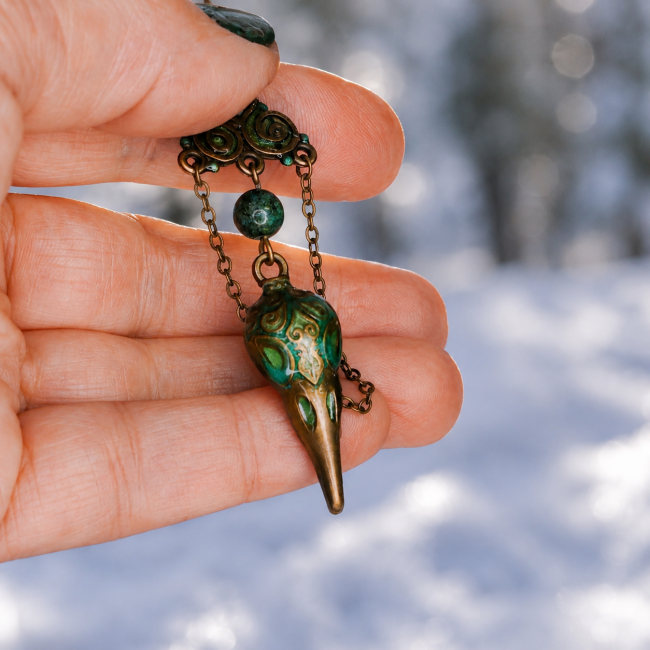 Zoom lumineux sur le triskel et les perles de chrysocolle d’un bijou artisanal inspiré des légendes nordiques et celtiques.