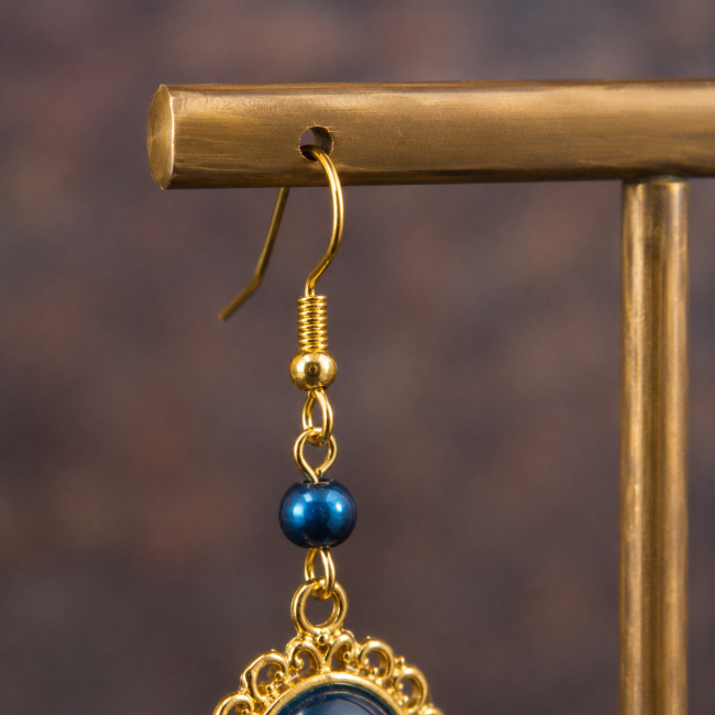 Attache crochet des boucles d'oreilles Le Sillage de l'Hippocampe Détail du crochet doré et de la perle en hématite bleue des boucles d'oreilles artisanales Le Sillage de l'Hippocampe.