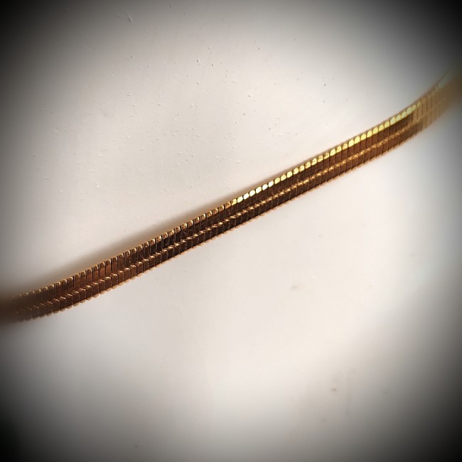 Chaîne serpent plate en acier inoxydable doré des colliers Isis par les Fantaisies d'A Monté sur une chaîne serpent plate, le collier Isis se ferme par un mousqueton sécurisé, complété par une chaînette de réglage terminée par une gemme et un médaillon émaillé signé Les Fantaisies d’A. Une seconde chaînette d’embellissement accueille une ai