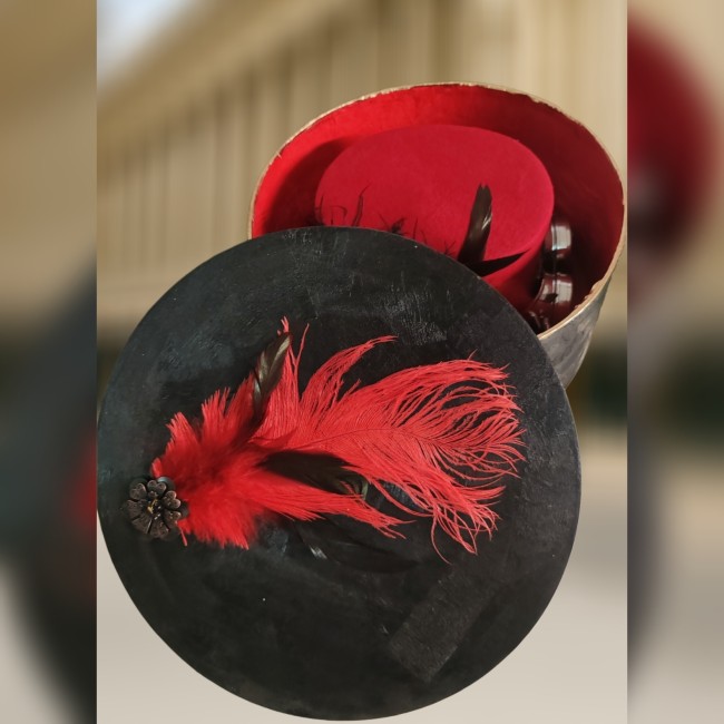 Chapeau steampunk gothique Dr Jekyll présenté dans sa boîte personnalisée avec plumes rouges et noires