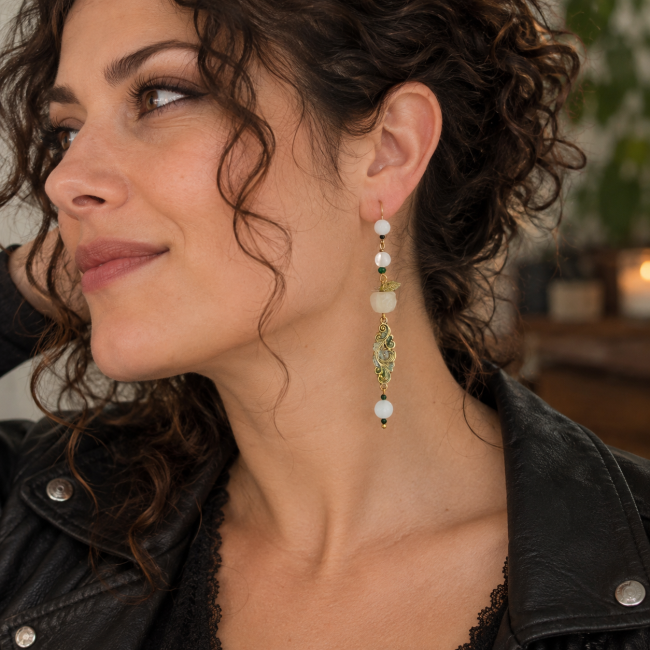 Boucle d’oreille Le Jardin d’Idunn portée – Création artisanale Deuxième boucle d’oreille Le Jardin d’Idunn portée par une femme brune aux cheveux bouclés avec veste rock.