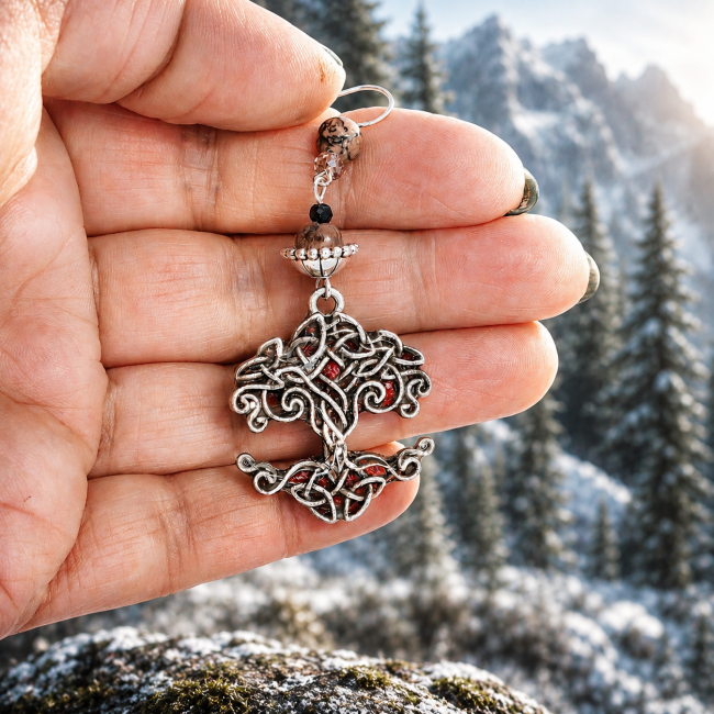 Boucles d'oreilles Arbre de Vie nordique portées en main – La Rosée de Heiðrún Vue détaillée du bijou permettant d'apprécier les dimensions réelles, l'émaillage artisanal et les perles de rhodonite. Création unique inspirée des légendes nordiques et du Valhalla.