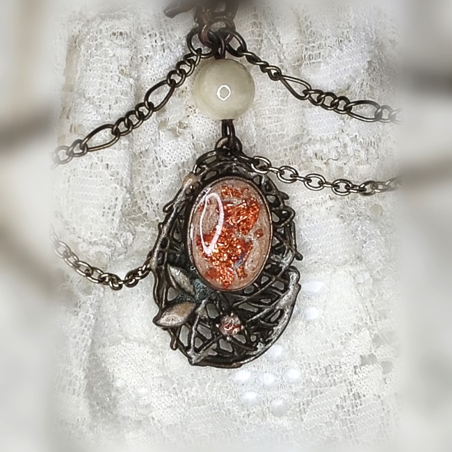 Gros plan sur le pendentif victorien du collier Cassandre, émaillage ivoire nacré avec inclusion de feuilles de cuivre et perle en opale blanche