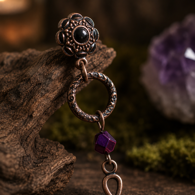 Détail de la puce et de l'hématite – Le Lien de Brigid Gros plan sur la puce d'oreille florale, l'anneau gravé et la perle d'hématite des boucles d'oreilles Le Lien de Brigid.
