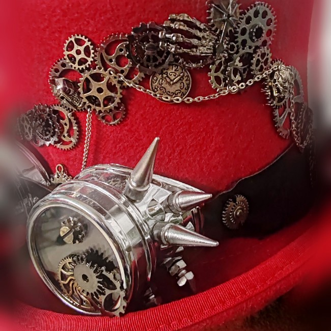Zoom sur engrenages, chaînettes et main squelette en métal argenté cousus à la main sur le chapeau steampunk Dr Jekyll