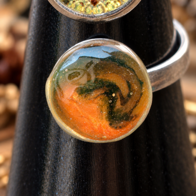 Vue rapprochée du cabochon aux nuances orange et sombres évoquant la silhouette mystérieuse d’un dragon endormi.
