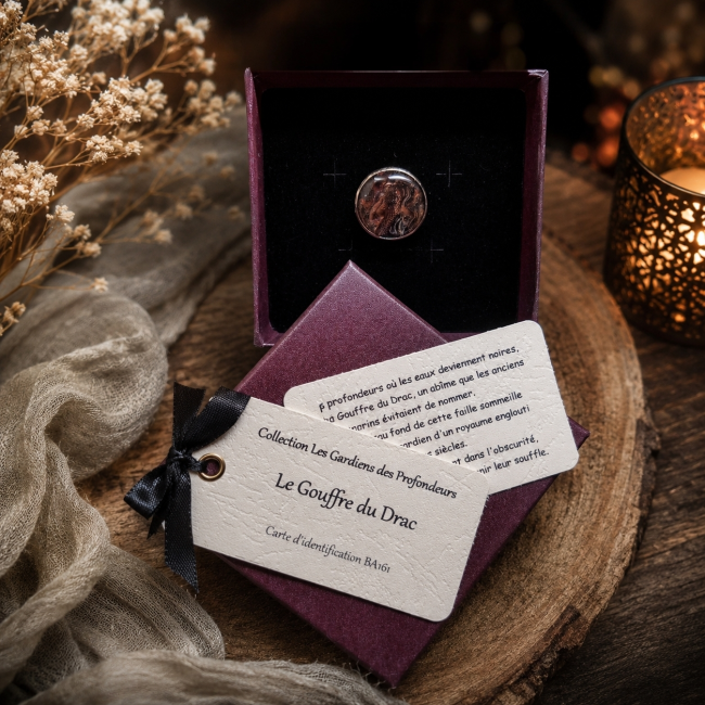 Le Gouffre du Drac présenté dans son écrin bordeaux, accompagné de sa carte d’identification, dans une ambiance chaleureuse et mystérieuse inspirée des profondeurs.