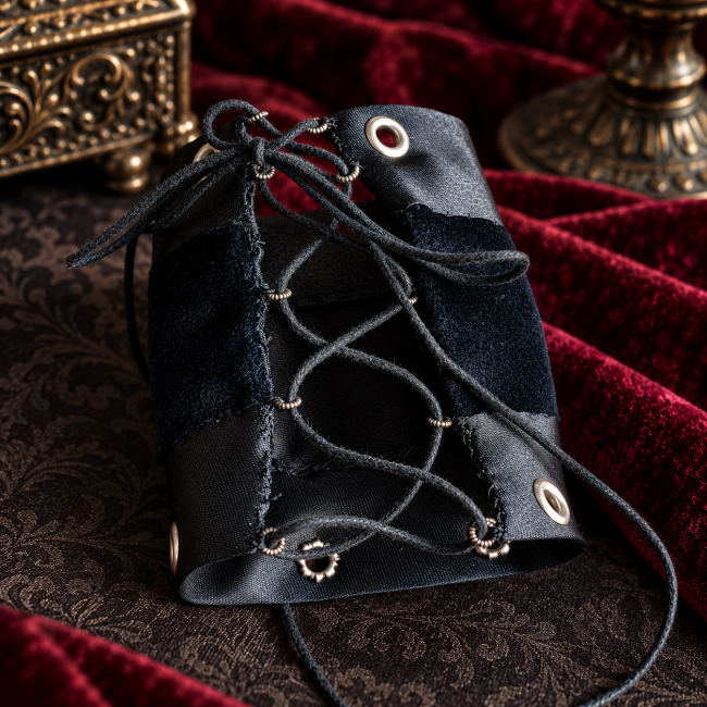 Vue arrière de la manchette gothique noire montrant sa fermeture à lacet croisé façon corset, ses œillets métalliques argentés et ses bandes de satin et de velours.