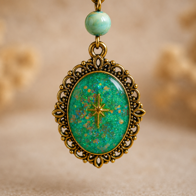 Gros plan sur le médaillon ovale d'inspiration victorienne, émaillé d'un turquoise scintillant et orné d'une délicate étoile elfique dorée au centre.