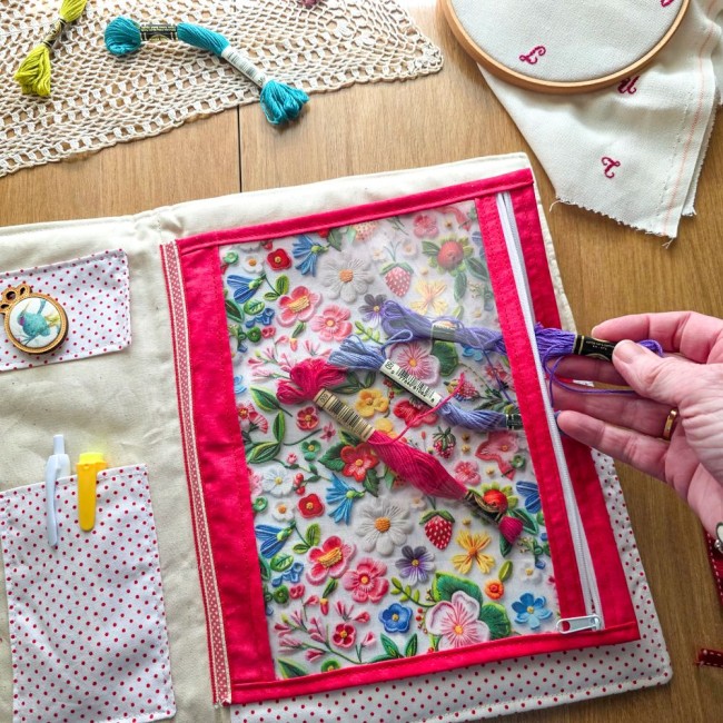 trousse-brodeuse-rangement-echevettes-pochette-zippee-alice-angelique-la-fee-en-fil Main glissant une échevette de fil à broder dans la pochette zippée en vinyle de la trousse Alice à pois rouges, création artisanale Angélique La Fée En Fil.
