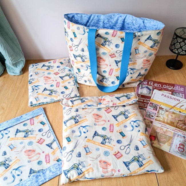 collection d'accessoire pour la broderie, sac cabas, pochette à projet, trousse de brodeuse et pochette rangement cadre à broder. Poser sur une table à côté de magazine de point de croix. Création Angélique La Fée En Fil