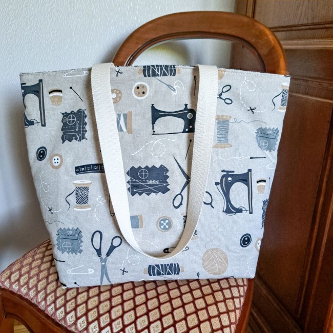 sac-projet-loisirs-creatif-angelique-la-fee-en-fil Posé sur une chaise un sac à bandoulière Louise beige motif imprimé noir des accessoires de couture. Création Angélique La Fée En Fil