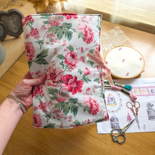 trousse-brodeuse-motif-fleurs-roses-sofia-en-main-point-de-croix-angelique-la-fee-en-fil Main tenant la trousse de brodeuse organisatrice fermée en tissu floral rose motif Sofia, montrant sa taille réelle. Crée par Angélique La Fée En Fil