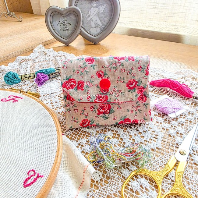 poubelle-a-fils-mini-pochon-broderie-fleuri-roses-vanille-angelique-la-fee-en-fil Mini poubelle à fils pliable en tissu lin naturel imprimé de petites roses rouges avec bouton-pression rouge. Posée sur un napperon en dentelle avec accessoires de broderie, création artisanale Angélique La Fée En Fil.
