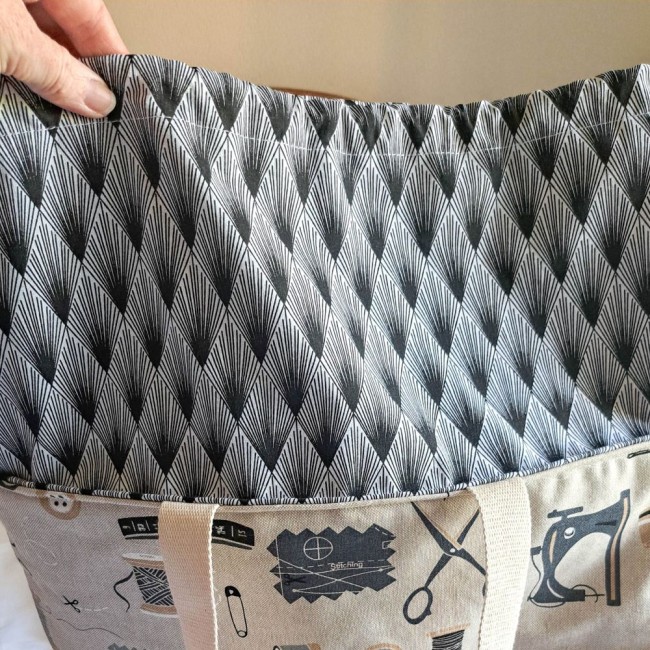 sac-cabas-tricotin-angelique-la-fee-en-fil tenu par la main de la créatrice Angélique La Fée En Fil, elle présente la réhausse du sac cabas Louise imprimé noir et blanc motif losange