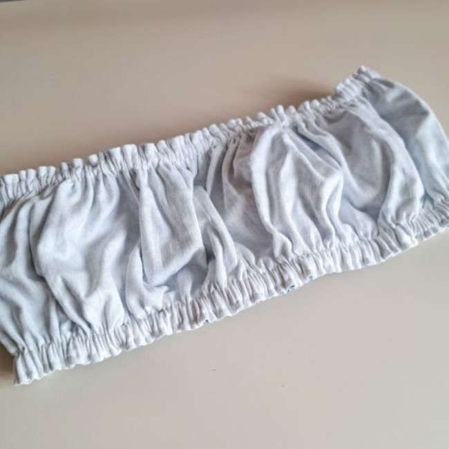 grime-guard-envers-coton-blanc-endroit-sous-bois-dore-la-fee-en-fil Vue de l'envers d'un grime guard froncé, montrant une doublure en tissu de coton blanc uni et propre, présenté à plat sur un fond neutre. Crée par Angélique La Fée En Fil