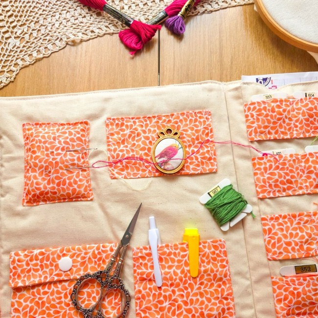 Vue de l'intérieur de la trousse de brodeuse Savannah avec poches en tissu orange à motif gouttes, pique-aiguille intégrée, ciseaux vintage et rangements pour cartonnettes, création artisanale Angélique La Fée En Fil.
