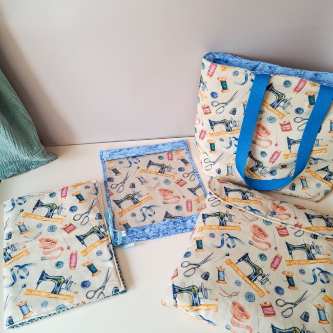 collection d'accessoire pour la broderie, sac cabas, pochette à projet, trousse de brodeuse et pochette rangement cadre à broder. Poser sur une table à côté de magazine de point de croix. Création Angélique La Fée En Fil