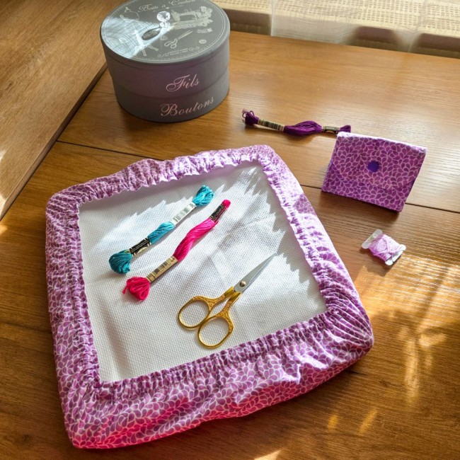 Vue d'ensemble d'un set assorti d'accessoires de broderie modèle Lavande en tissu coton violet à motifs feuillage, comprenant un grime guard housse protège-toile sur cadre Q-Snap carré et une mini poubelle à fils pliante, avec ciseaux dorés, échevettes et