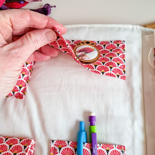 Trousse de brodeuse artisanale en tissu japonais rouge à motifs éventails, avec emplacement pour ciseaux, stylos et fils à broder, création Angélique La fée En Fil, présentée avec échevettes colorées.