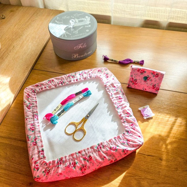 Ensemble d'accessoires de broderie assortis modèle Romane comprenant une mini poubelle à fils pliable et une housse protège-toile pour tambour carré en tissu rose imprimé de roses rouges, accompagnés de ciseaux dorés, d'échevettes et d'une boîte à couture