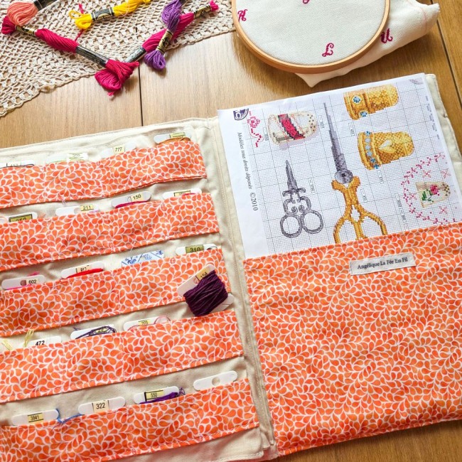 Vue d'ensemble de la trousse de brodeuse Savannah ouverte à plat, avec rangements pour cartonnettes en tissu orange à motif gouttes et grille de broderie insérée dans la grande poche, création artisanale Angélique La Fée En Fil.