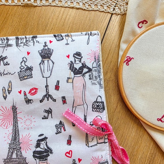 Gros plan de la trousse de broderie Nina mettant en valeur le ruban d'attache rose et le motif imprimé Paris chic avec la Tour Eiffel et des éléments de mode, création artisanale Angélique La Fée En Fil.